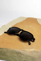 Lentes de sol negros con marco aviador y lentes oscuros.