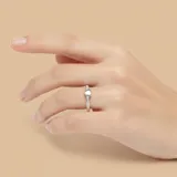Anillo de plata 925 con una banda pavimentada con circonias y un dije central en forma de corazón liso y blanco.