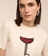 Remera de algodón color crema con cuello redondo y mangas cortas. Estampa frontal de una copa de Cosmopolitan y la inscripción "Cosmopolitan".