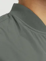 Campera bomber verde militar, de manga larga con cuello baseball y fit cómodo. Diseño con cierre frontal de cremallera, bolsillos delanteros funcionales y puños de canalé.