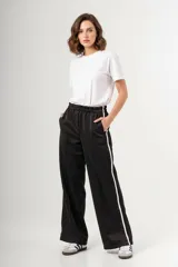 Pantalón negro de tela deportiva estilo retro, corte amplio y cintura elástica.