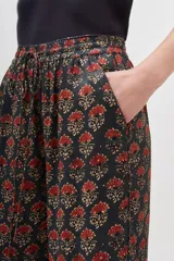 Conjunto de pantalón y kimono con estampado floral en tonos rojos y dorados sobre fondo negro. El pantalón es de corte palazzo y el kimono tiene mangas anchas.