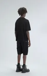 Remera negra de tejido de punto con moldería oversize, confeccionada en viscosa y poliéster. Presenta un diseño de malla con pequeños agujeros y un dobladillo acanalado.