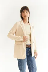 Blazer beige de tela agamuzada, corte recto y solapas clásicas.