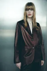 Blazer de cuero color marrón chocolate con cuello solapa, cierre frontal con dos botones, bolsillos de vivo y abertura en la espalda.