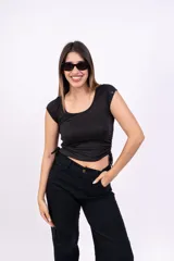 Remera negra de corte crop con escote redondo y mangas cortas. Presenta cordones ajustables en los laterales.