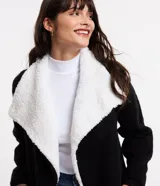 Cardigan alargado color blanco, con cuello virada, forro de pelos y confeccionado en punto pesado. No tiene cierre.