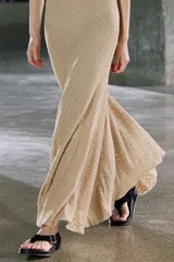 Vestido midi de encaje color beige, sin mangas, con espalda descubierta y bajo asimétrico con volados.