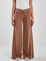 Pantalón de jean color marrón óxido, estilo ancho (wide leg) con tiro alto, pliegues frontales y posteriores, y diseño de cinco bolsillos.