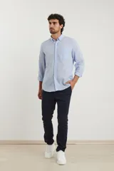 Camisa azul marino de lino y algodón, con cuello abotonado, manga larga con puños enrollados, bolsillo de parche en el pecho y cierre frontal con botones.