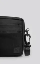 Mini bolso negro de estilo modular, confeccionado en tejido tracker impermeable. Presenta tres compartimentos con cierre y correa ajustable para llevar al hombro o cruzado.