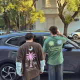 Camiseta marrón de corte oversize, con estampa en serigrafía bicolor (blanco y rosa) de una palmera, una luna y el logo de la marca.