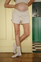 Conjunto de pijama color beige, compuesto por un top de mangas cortas con ribete marrón y shorts con ribete marrón.