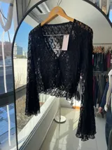 Blusa de encaje negro con mangas largas acampanadas y escote en V.