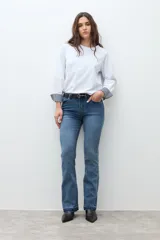 Remera blanca de manga larga con puños doblados que muestran un estampado vichy (cuadros) en azul marino y blanco. Tiene cuello redondo y un calce relajado.