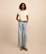 Pantalón wide leg de jeans marmorizado celeste, con bolsillos delanteros y traseros, cintura con trabillas, cierre con botón y cremallera, y abertura lateral en el bajo.