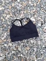 Top deportivo negro con breteles regulables y padding desmontable, ideal para actividades físicas.