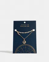 Collar corto dorado de doble cadena, una con círculos pequeños y otra con dije de metal con piedra azul.