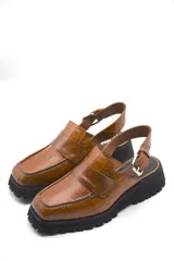 Zueco tipo mocasín color marrón con textura croco y tira regulable al talón.
