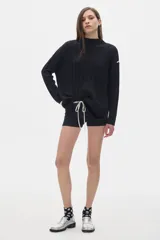 Buzo tejido color crema con cuello alto tipo polera, corte oversized y aberturas laterales.