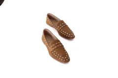 Mocasín de gamuza color tostado con detalles de tachuelas metálicas.