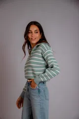 Sweater de punto color beige con rayas horizontales blancas, cuello polo con cierre de cremallera y mangas largas.