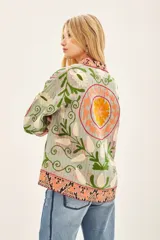 Saco corto estilo kimono con bordado gudri y estampado floral en tonos naranja, verde y gris.