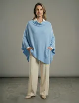 Poncho tejido de punto grueso, color mostaza/mostaza oscuro, con cuello redondo y caída amplia.