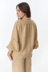 Camisa celeste de lino con botones, mangas largas abullonadas y detalles de crochet en el frente y los puños.