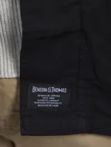 Camisa gruesa de gabardina color azul marino, con cuello clásico, cierre frontal con botones a presión, cuatro bolsillos frontales con solapa y puños abotonados.