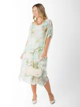 Vestido dos en uno confeccionado en seda italiana, con capa superior de calce amplio y falda con volados que aportan movimiento. Incluye forro en algodón elastizado.