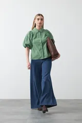 Camisa blanca de algodón con cuello camisero y mangas cortas abullonadas. Presenta un corte relajado y cierre frontal de botones.