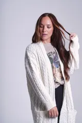 Saco tejido color crema con diseño de ochos y bolsillos frontales.