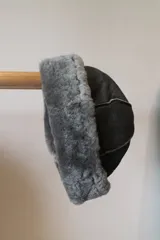Gorro negro de cuero con borde de corderito gris.