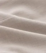 Chaleco color beige con escote halter, corte al cuerpo y cierre frontal con botones. Presenta un bolsillo de ojal en el frente.