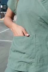 Blusa color beige con cuello camisero, corte cruzado, mangas cortas y lazo lateral.