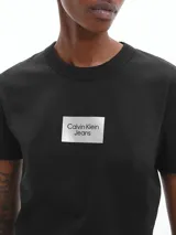 Remera negra de corte slim fit, cuello redondo y manga corta. Presenta un logo rectangular de Calvin Klein Jeans en el pecho.