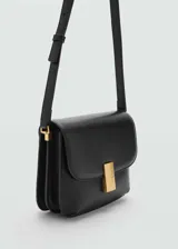 Bolso bandolera de cuero sintético color negro, con forma rectangular y cierre con broche metálico dorado.