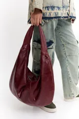 Bolso de cuero negro con diseño minimalista y espacioso, adecuado para llevar múltiples objetos.