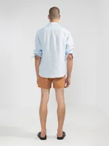 Camisa celeste de lino, de manga larga con botones de coco y parche de la marca.