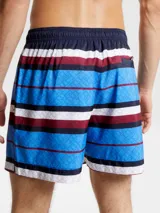 Short de baño Tommy Hilfiger con estampado de rayas horizontales en azul, blanco y rojo. Diseño con monograma TH estampado en azul sobre las rayas azules. Cintura elástica con cordón ajustable.