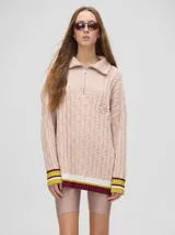 Sweater tejido de algodón color rosa claro, con cuello polo con cierre de cremallera metálica y mangas largas con puños a rayas de colores.