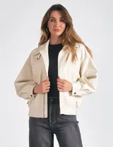 Campera bomber color beige de eco cuero, marca Elan. Tiene cuello con solapa y botón a presión, cierre metálico central, bolsillos delanteros con solapa y botón a presión, y ruedo trasero elastizado.