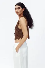 Chaleco marrón de crochet con escote en pico y cierre frontal con lazos.