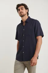 Camisa sport de manga corta color verde oliva, línea premium, con cuello clásico, cierre frontal con botones de coco y bolsillo de parche en el pecho. Confeccionada en lino y algodón.