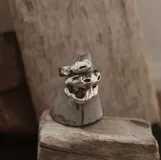 Anillo plateado con forma orgánica irregular, similar a un crustáceo marino.