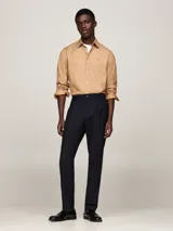 Camisa color beige de corte regular, confeccionada en algodón elástico. Cuenta con cuello abotonado, mangas largas con puños abotonados y logo de Tommy Hilfiger bordado en el pecho.