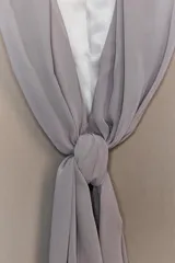 Blazer color beige con cuello solapa, manga larga con abertura y detalle de lazo gris en el frente.