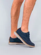 Zapato acordonado azul marino, con capellada combinada en cuero y tejido de red. Suela blanca de goma con vira marrón.