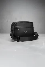 Bandolera negra de cuero sintético con correa ancha ajustable y desmontable. Cuenta con cierre superior, bolsillo frontal con tiracierre customizado, forro interno y cuatro bolsillos en total (dos exteriores y dos interiores).